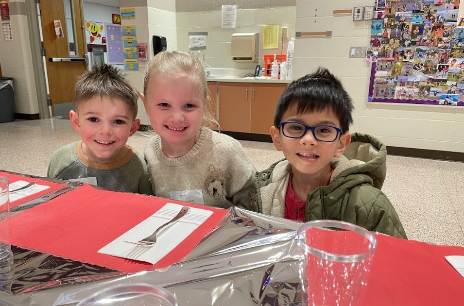 Two male students and one female student smiling proudly at the camera.