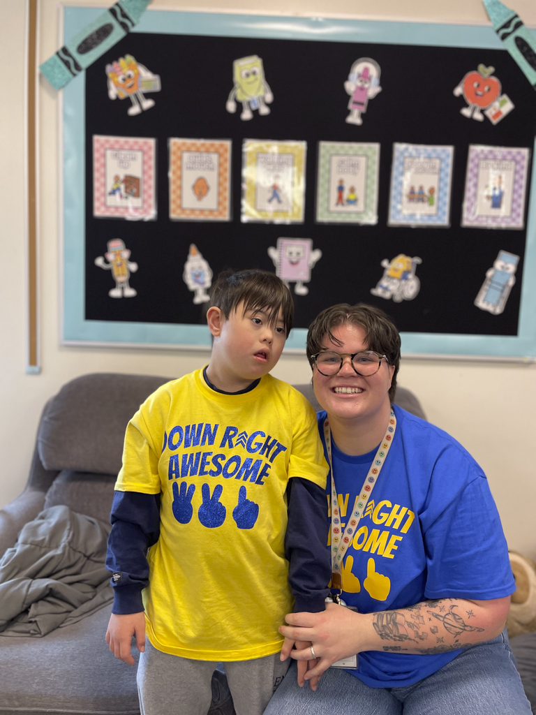 A student and teacher pose together for a picture during class.
