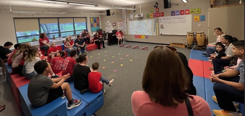 Students and parents sitting in music room smiling