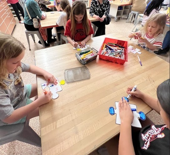 Students at a table coloring puzzle pieces