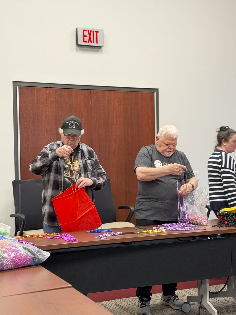 Two volunteers stuff goodie bags with colored necklaces for CV's Special Olympics.