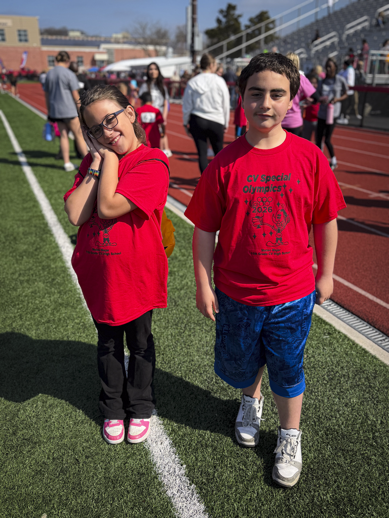 Two students in red shirts smile for a picture while standing on Chapman Field during CV's Special Olympics.