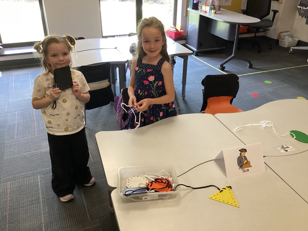 Kindergarten students practice colonial-era tailoring by lacing shapes during a Colonial Towns classroom activity.