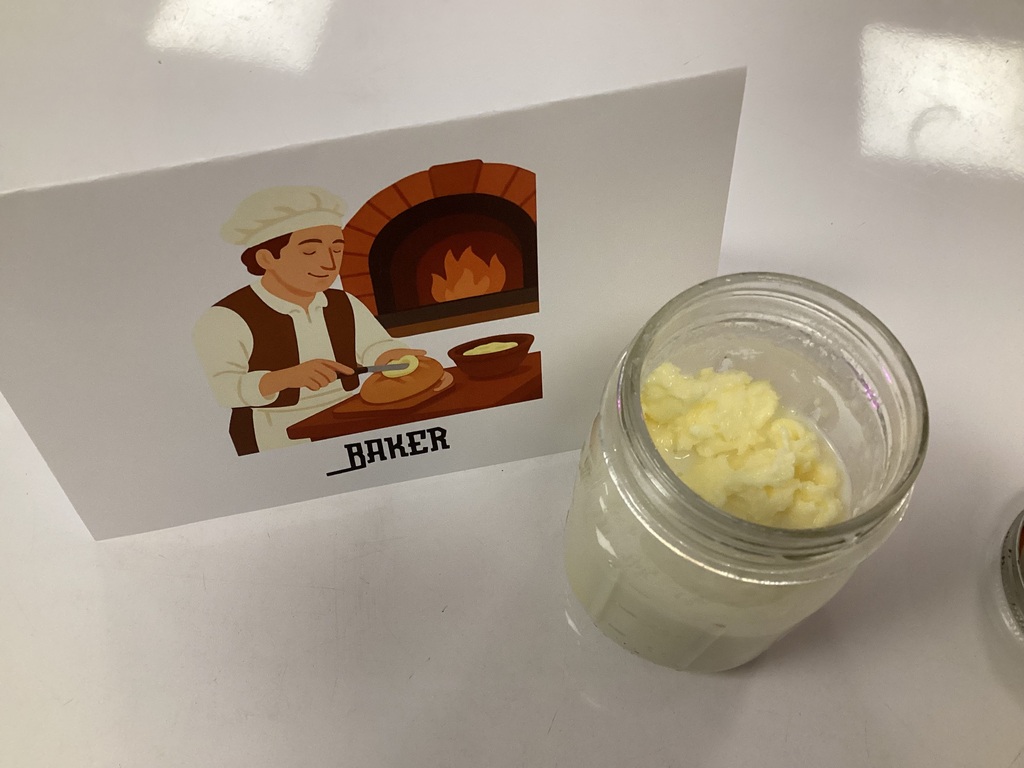 Jar of freshly made butter beside a “Baker” sign during a Kindergarten Colonial Towns activity.