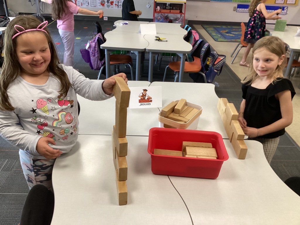Kindergarten students stack wooden blocks as bricklayers during a Colonial Towns classroom activity.