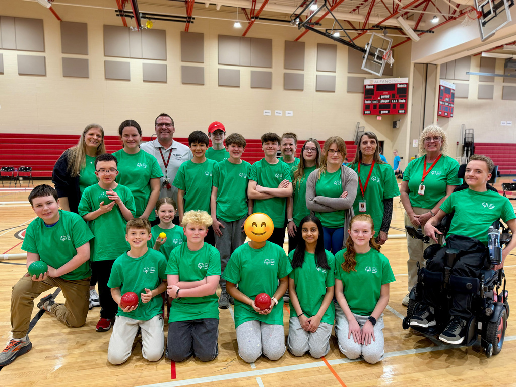 Eagle View Middle School unified bocce team gathers in a gym during the middle school bocce game, wearing matching green shirts and holding bocce balls.