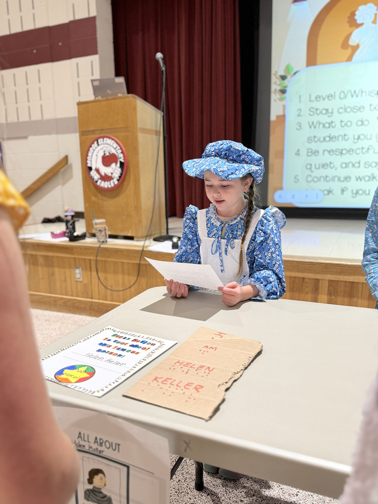 A Monroe Elementary second-grader portraying Helen Keller stands as a wax museum exhibit and reads facts about the historical figure to visitors.