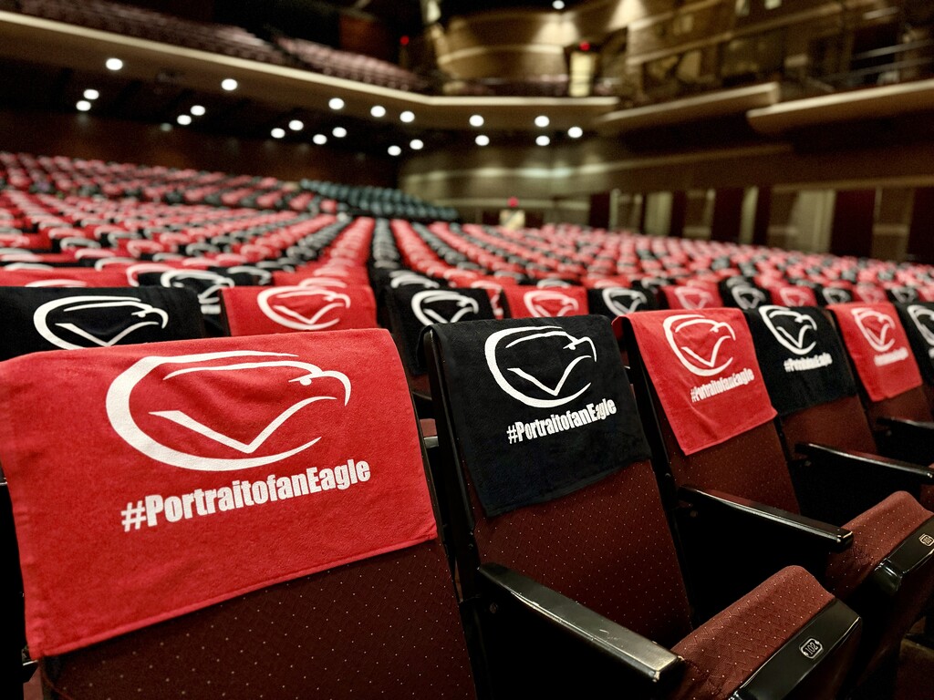 Red and black CV rally towels featuring the #PortraitofanEagle logo are displayed on auditorium seats before the 2026-27 Convocation.