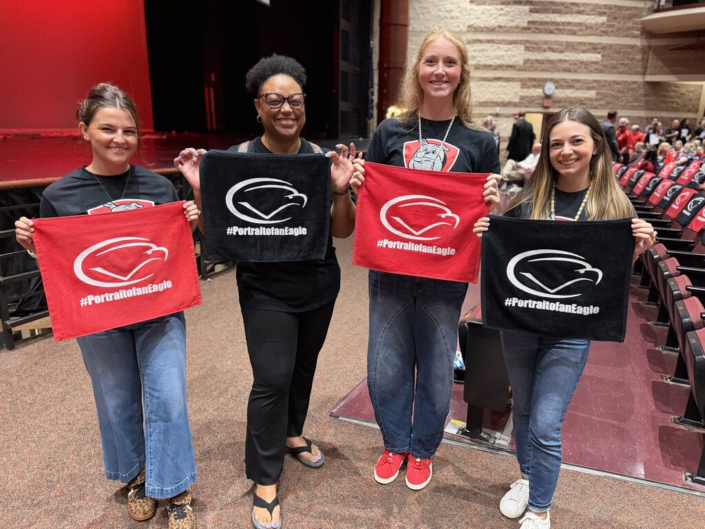 Four staff members display CV rally towels while posing in the Cumberland Valley High School Performing Arts Center during the 2026-27 Convocation.