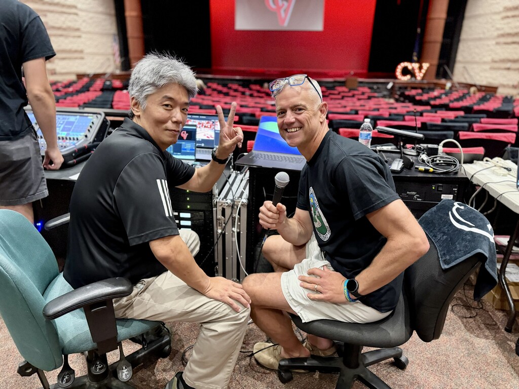 Two staff members from the convocation production team pose at the audio-visual control station before the 2026-27 Convocation.