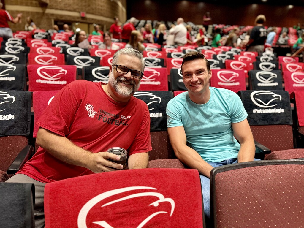 Two staff members sit among rows of CV rally towels before the start of the 2026-27 Convocation.