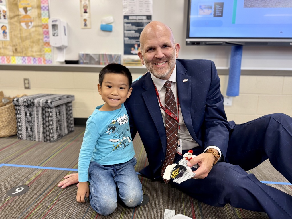 CV Superintendent, Dr. Blanchard, sits on the floor with a Kindergarten student, holding a lego ship the two built together.
