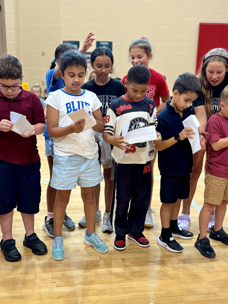 Students gather in the gym, opening envelopes to discover their House assignments during Winding Creek Elementary’s House Assembly.