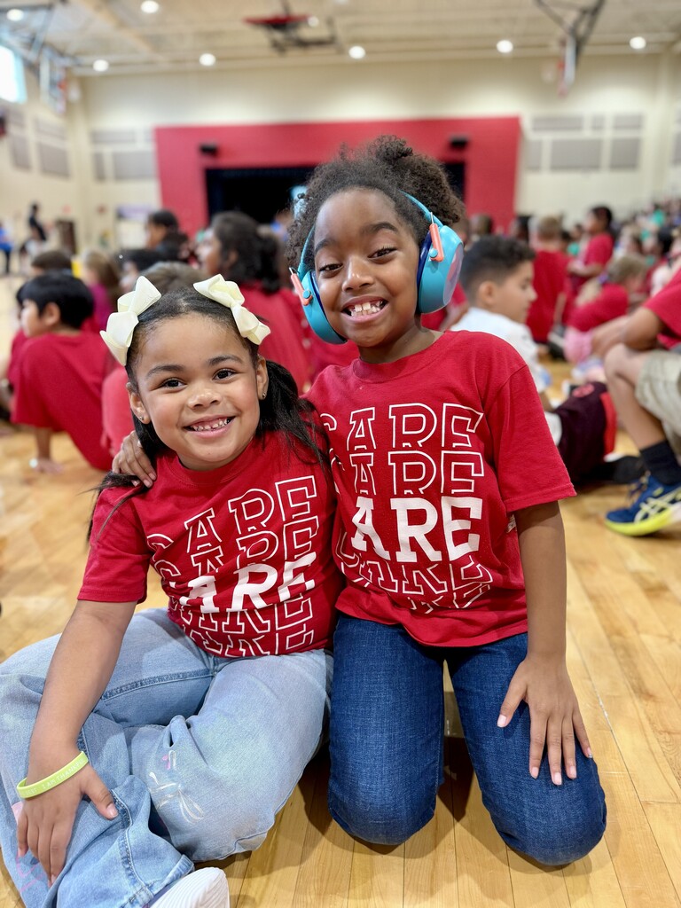 Two students in red House shirts pose together during Winding Creek Elementary’s House Assembly in the school gym.