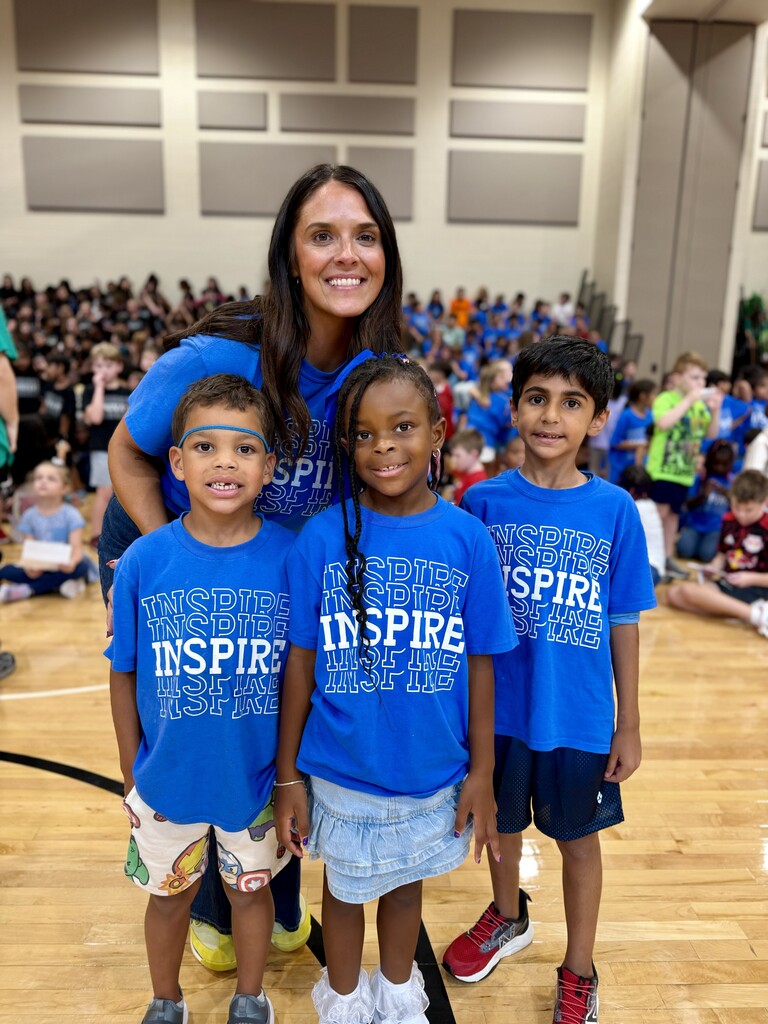 Principal Mrs. Stanford poses with three students wearing blue House shirts during Winding Creek Elementary’s House Assembly in the school gym.