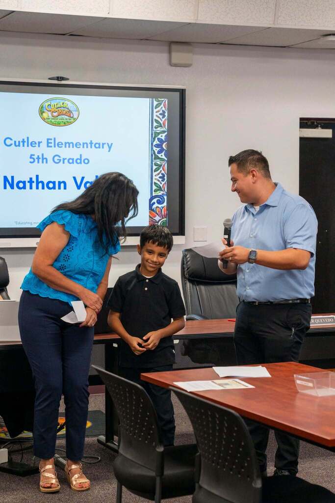 student smiling between staff as he is recognitzed