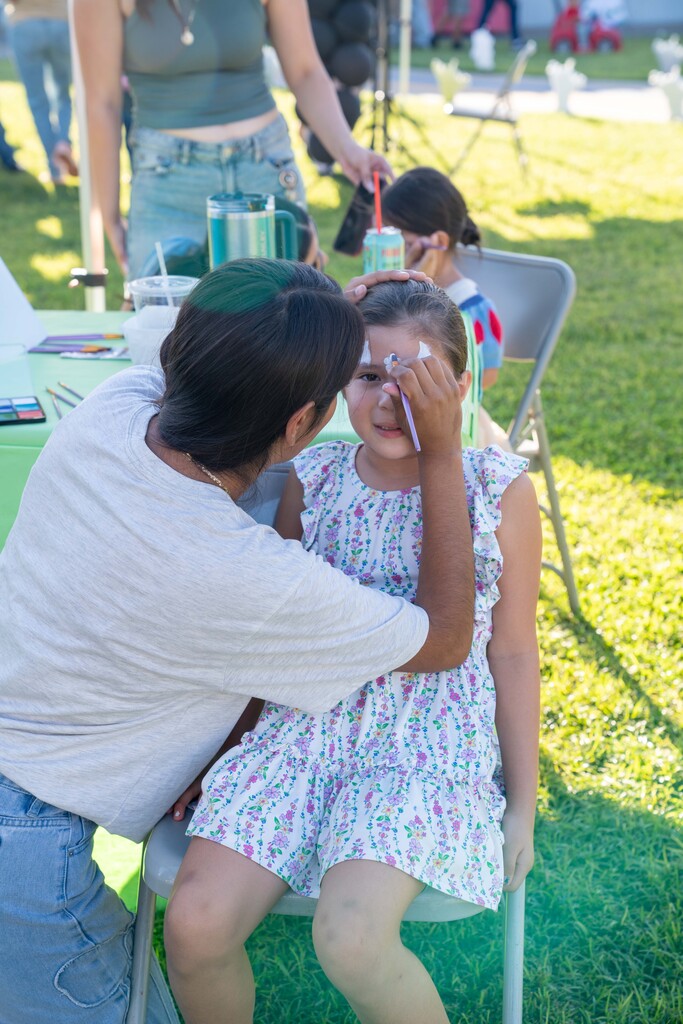 little girl is getting her face painted at the Cutler School Carnival
