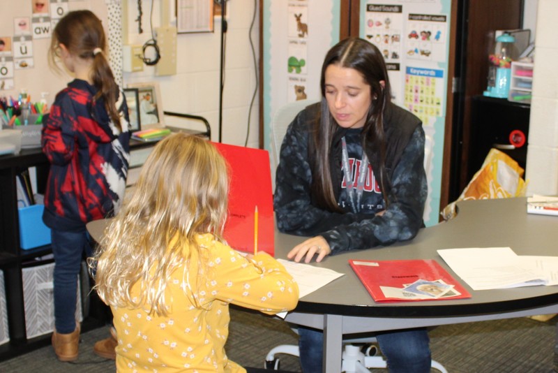 Female students working with a teacher at a table.