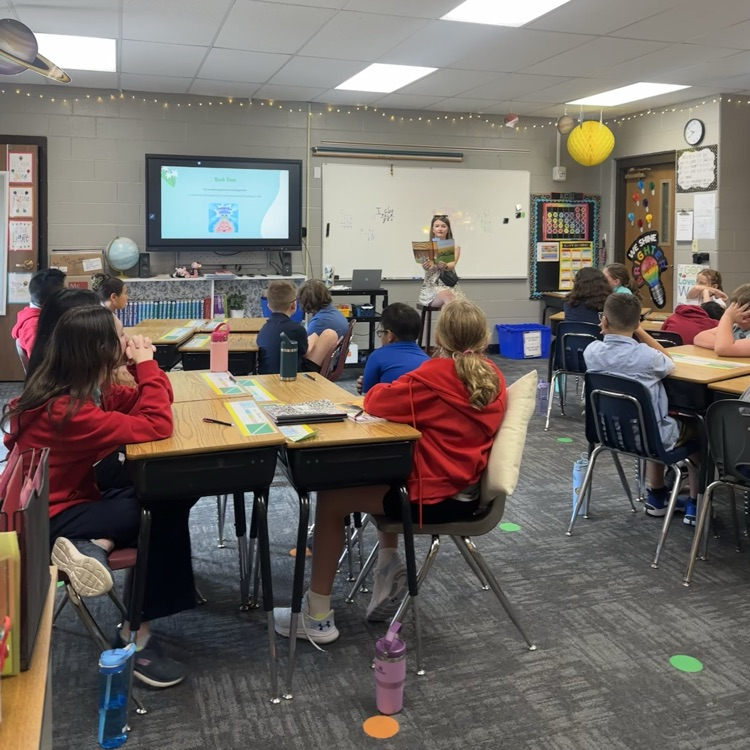 students listening to school counselor read a book