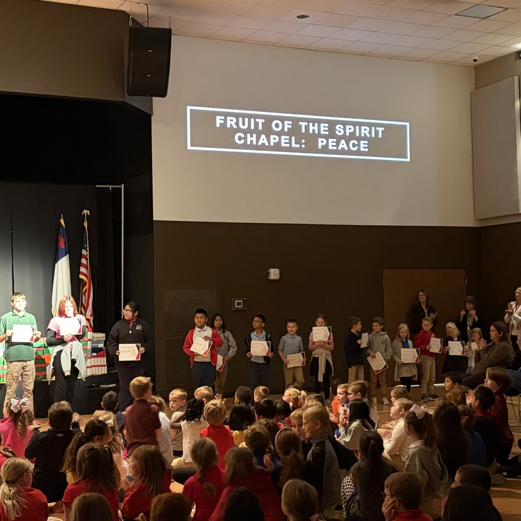 fruit of the spirit award recipients standing at the front of chapel holding  up their awards