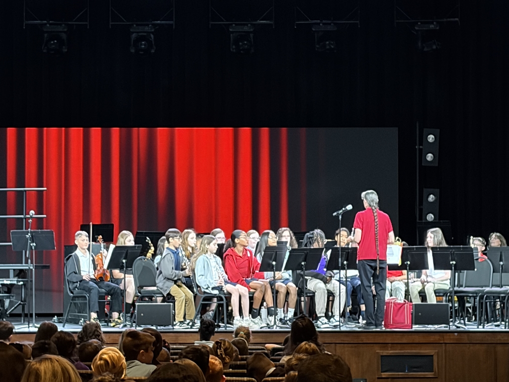 5th grade band member sitting on stage preparing to perform