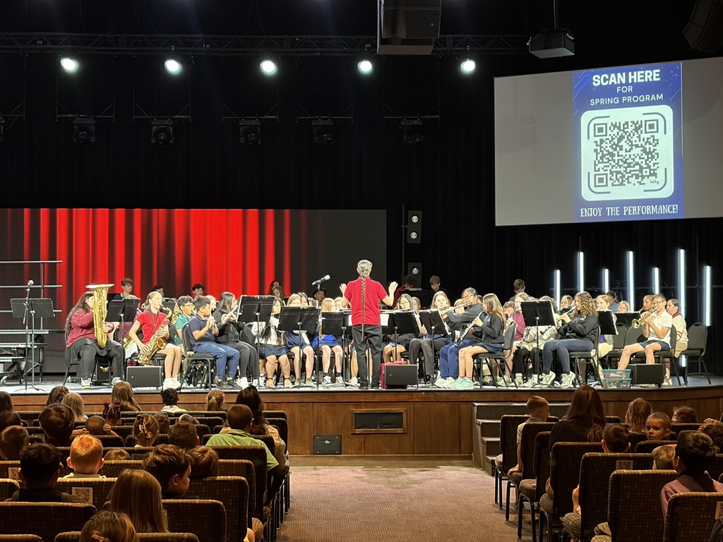 middle school band members sitting on stage preparing to perform