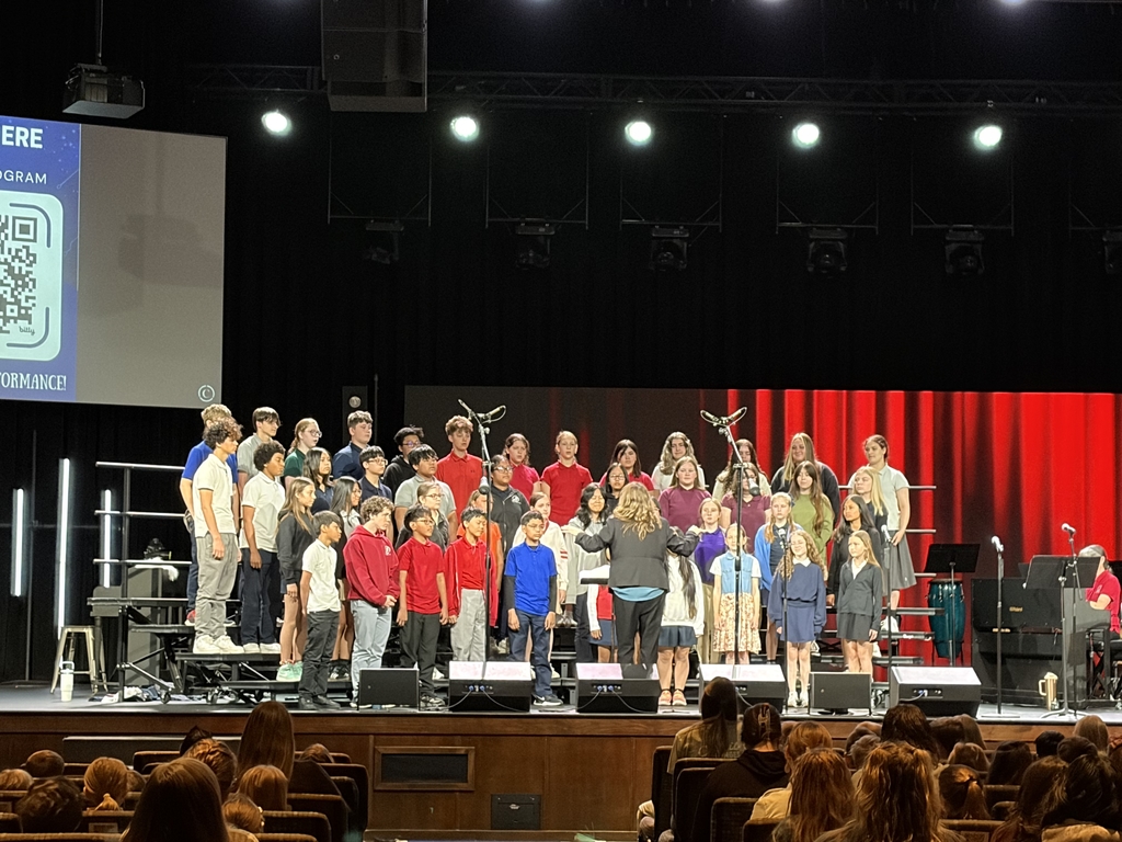middle school choir members standing on risers preparing to perform