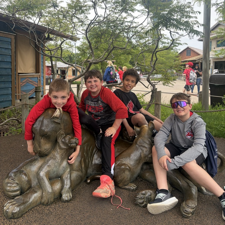 Second grade students posing on a bronze statue