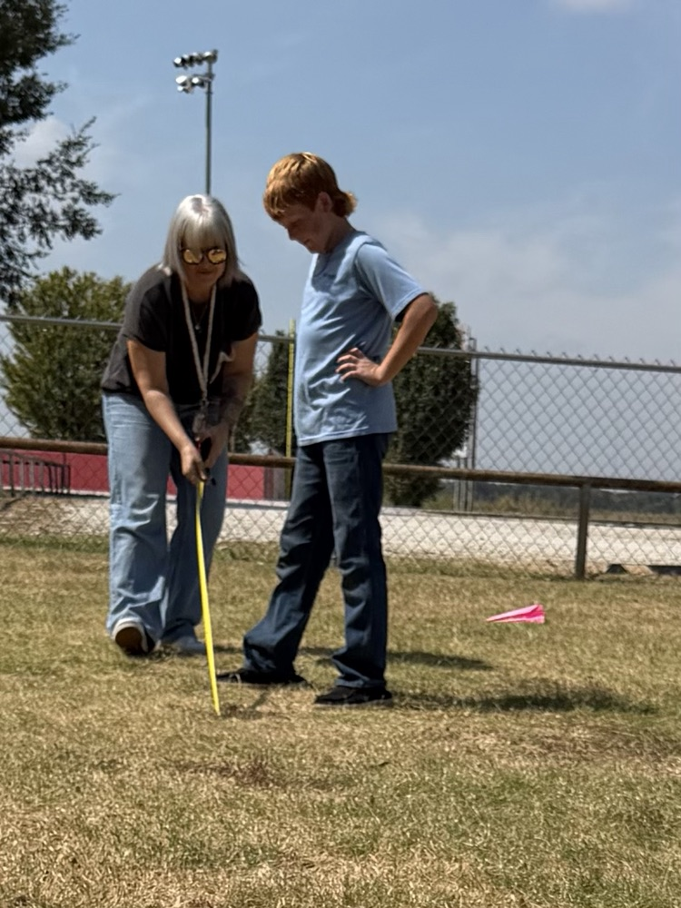 A student and a teacher using a tape measure