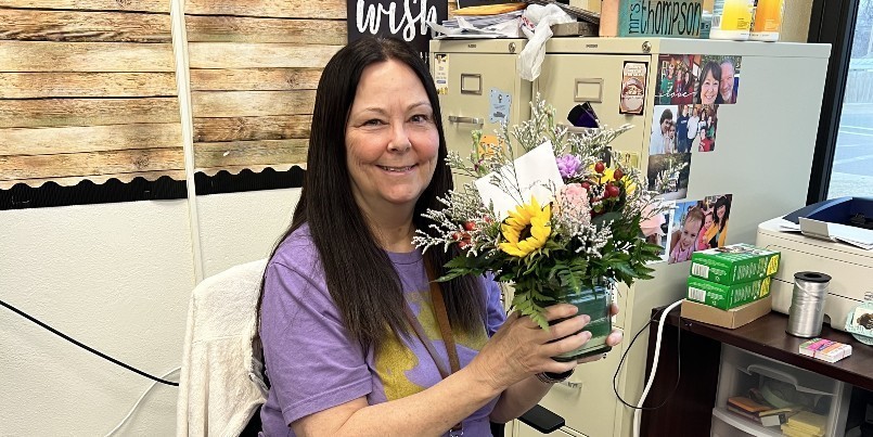 Photo of Diane Thompson holding flowers for counselor's week.