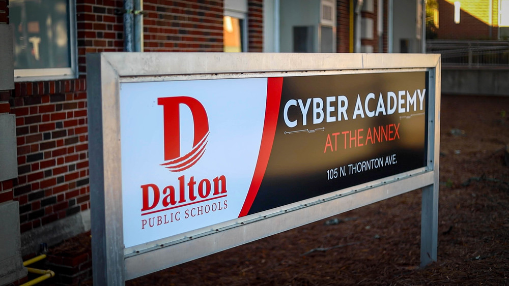 Exterior sign reading “Dalton Public Schools Cyber Academy at The Annex” displayed outside a brick building.