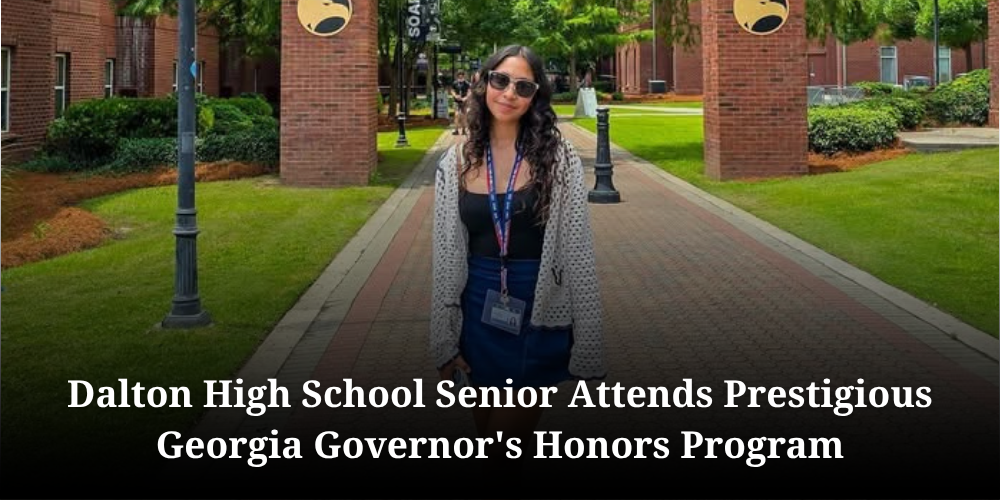 A news banner graphic titled "Dalton High School Senior Attends Prestigious Georgia Governor's Honors Program" in white bold text across the bottom. The background photo features a young woman with long wavy hair and sunglasses standing outdoors on a brick university pathway framed by brick pillars and greenery. She wears a black top, blue skirt, cream crocheted cardigan sweater, and a name badge lanyard around her neck.