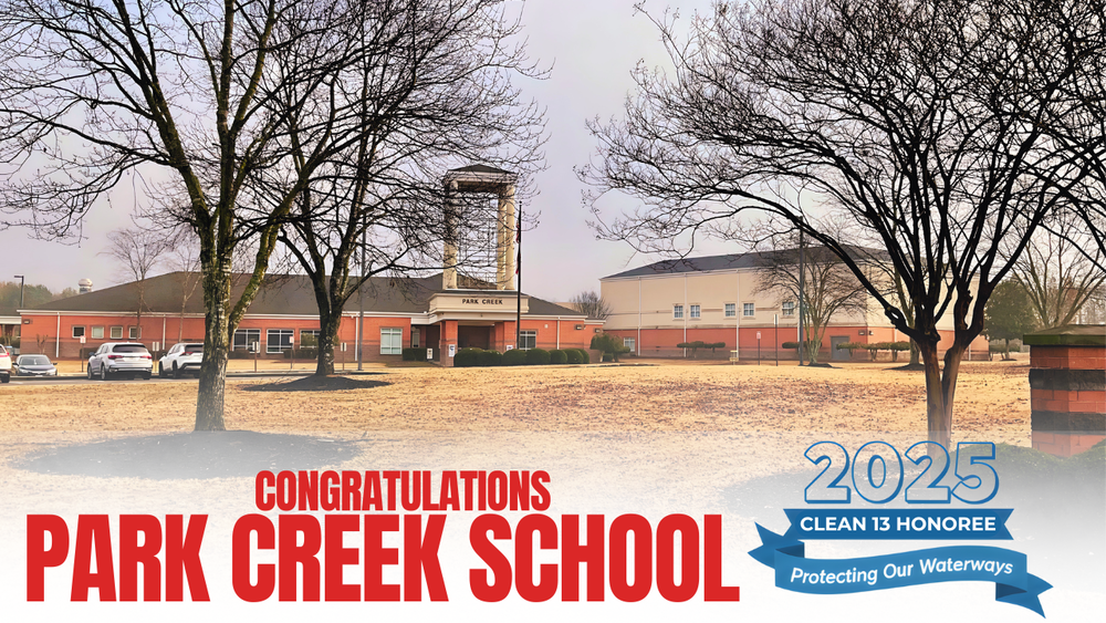 Exterior view of Park Creek Elementary School with bare winter trees in front and cars parked by the entrance. Overlaid text reads “Congratulations Park Creek School” in bold red letters, alongside a blue ribbon graphic stating “2025 Clean 13 Honoree – Protecting Our Waterways.” The image celebrates the school’s recognition by the Georgia Water Coalition.