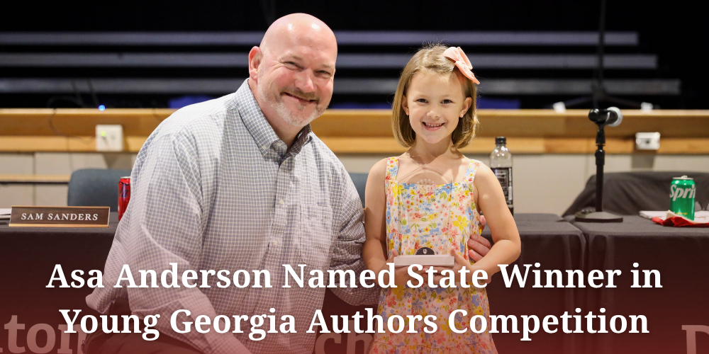A promotional graphic announcing that Asa Anderson was named a state winner in the Young Georgia Authors Competition. The image shows a smiling young girl in a colorful floral dress with a pink bow in her hair standing beside a smiling man in a checkered button-down shirt. They appear to be at a school board or recognition event, with microphones and tables visible in the background. Large white text across the lower half of the image highlights Asa’s achievement.