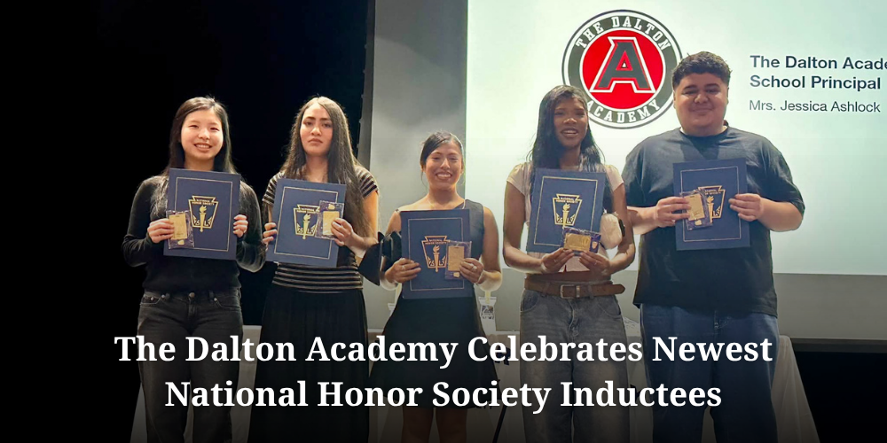 A wide promotional graphic honoring new National Honor Society members at The Dalton Academy. Five smiling high school students stand side-by-side on stage, each proudly holding a navy blue National Honor Society certificate folio and an induction pin card. A presentation screen in the background displays The Dalton Academy logo along with text listing Principal Mrs. Jessica Ashlock. Across the bottom of the graphic, bold white text reads "The Dalton Academy Celebrates Newest National Honor Society Inductees".