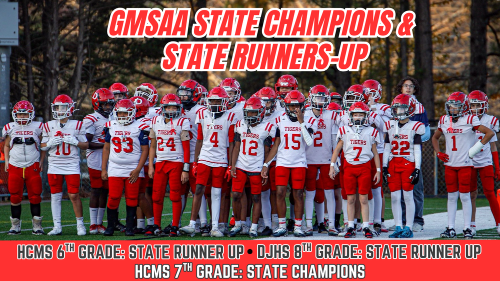 A large group of middle school football players in red and white Dalton Tigers uniforms stand together on the field, facing forward in a team huddle-like formation. Bold red text above the players reads “GMSAA State Champions & State Runners-Up.” A red banner along the bottom lists the results: “HCMS 6th Grade: State Runner Up • DJHS 8th Grade: State Runner Up • HCMS 7th Grade: State Champions.” The players appear focused and unified, wearing helmets and pads, with trees and a fence blurred in the background.