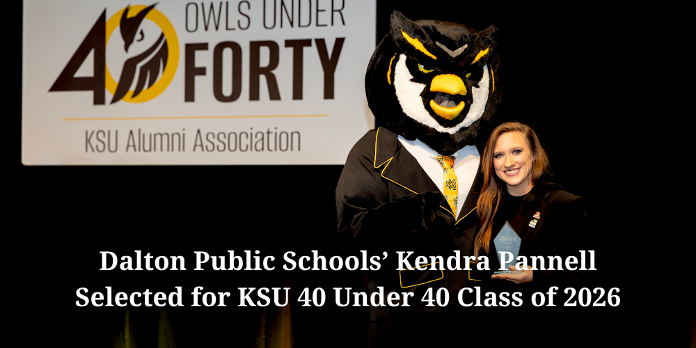 A promotional graphic announcing that Dalton Public Schools’ Kendra Pannell was selected for the KSU 40 Under 40 Class of 2026. The image features Kendra smiling while holding an award beside the Kennesaw State University owl mascot dressed in a tuxedo-style outfit. In the background is a large “40 Owls Under Forty – KSU Alumni Association” sign. Bold white text across the bottom highlights her recognition.