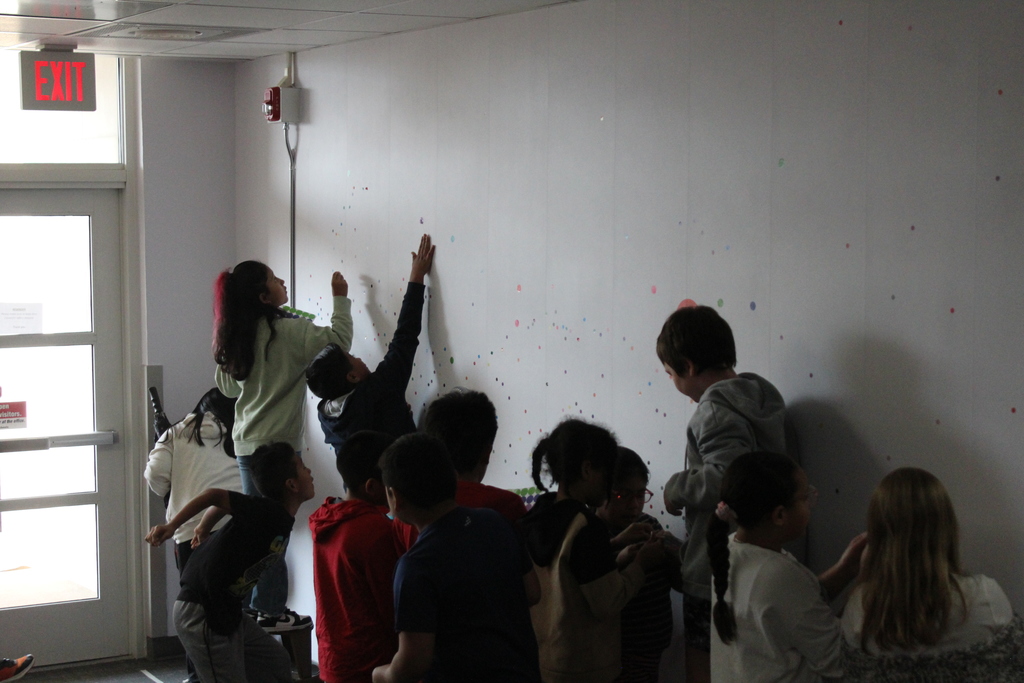 Students placing dots on wall 