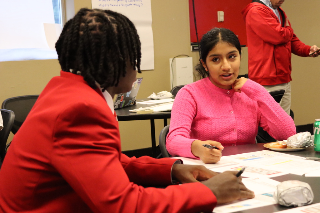 Two students sit across from each other in conversation, collaborating during the Student Advisory Council meeting.