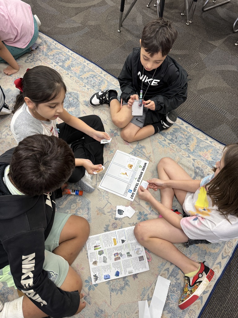 Students using recycling guides to sort trash