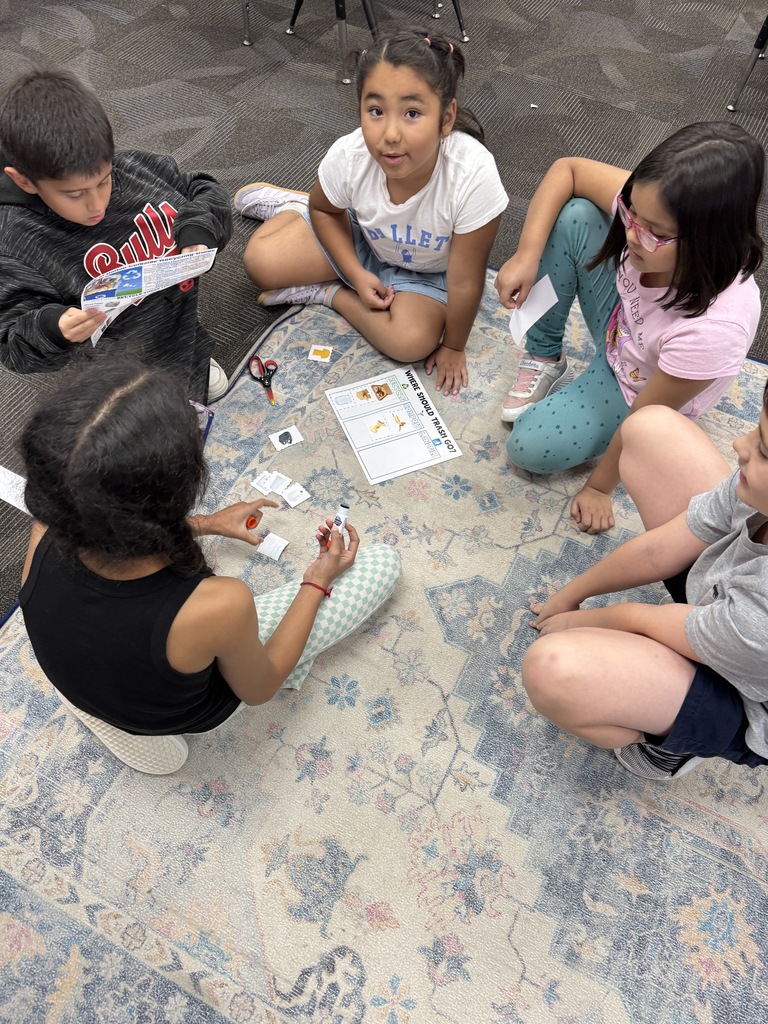 Students using recycling guides to sort trash