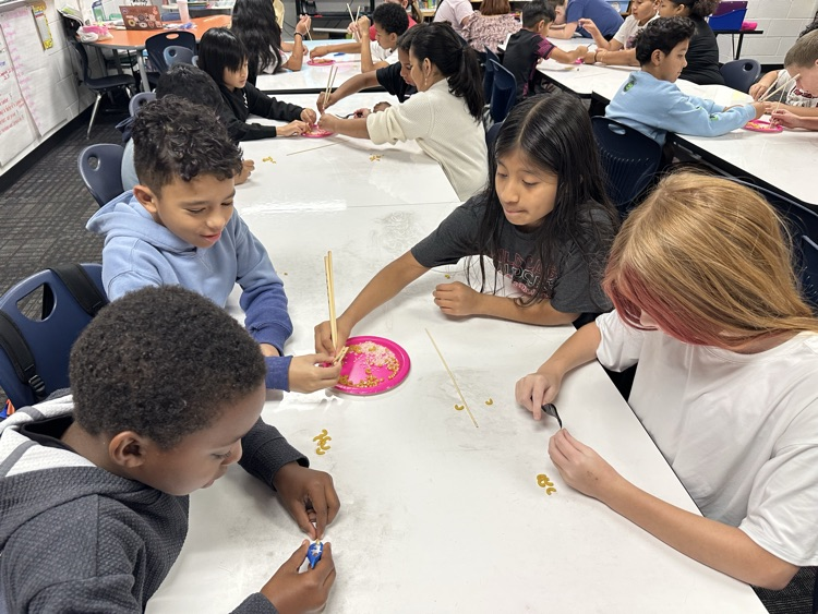 Students trying to pick up food using chopsticks