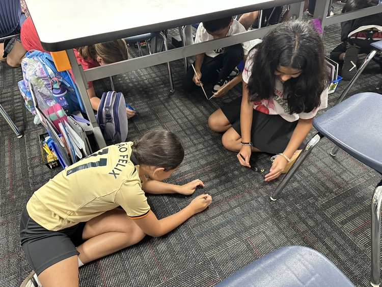 Students trying to pick up food from the floor using a fork