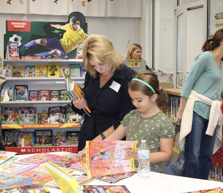 A student looking a book with her grandmother 
