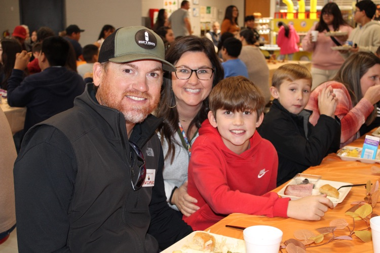 A student enjoying lunch with his parents