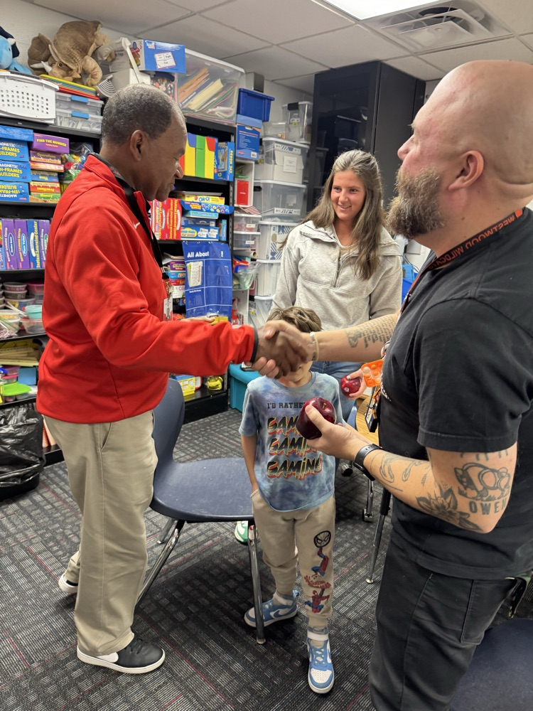 Mr. Tulley giving an apple to Mr. Baron and Ms. Johnson