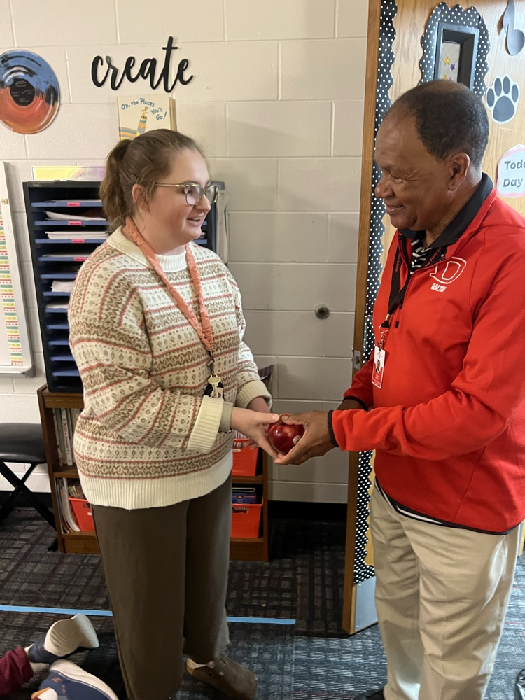 Mr. Tulley in the music room giving an apple to Mrs. Cantrell