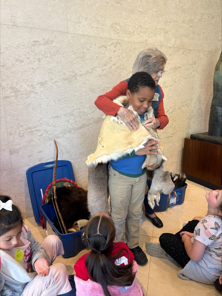 Student trying on a piece of clothing at the museum 