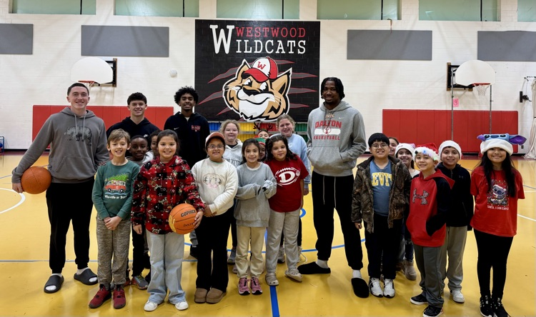 Basketball players playing with students during PE class