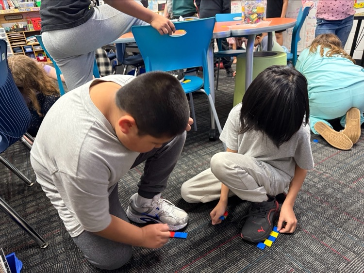 Two students measuring their shoes with small tiles